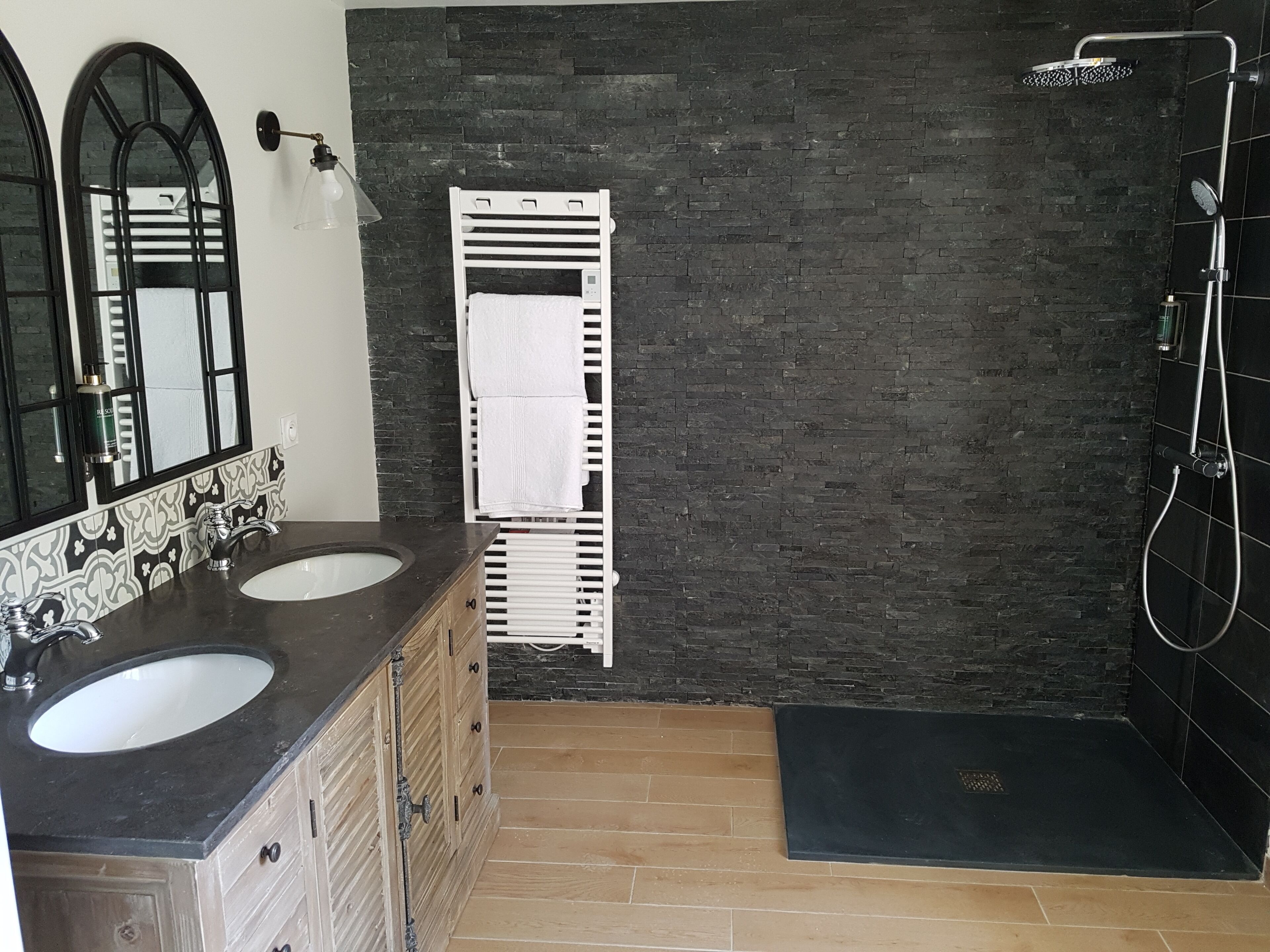 A bathroom with two sinks, a mirror, a towel rack, and a shower area.