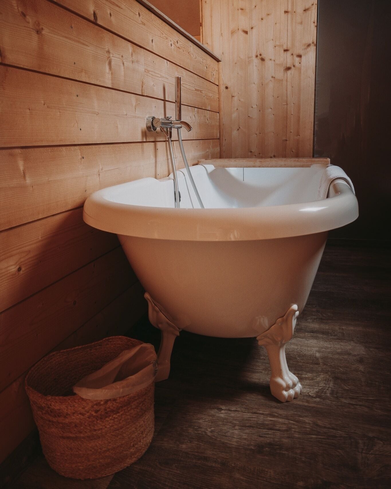 A clawfoot bathtub in a wooden room.