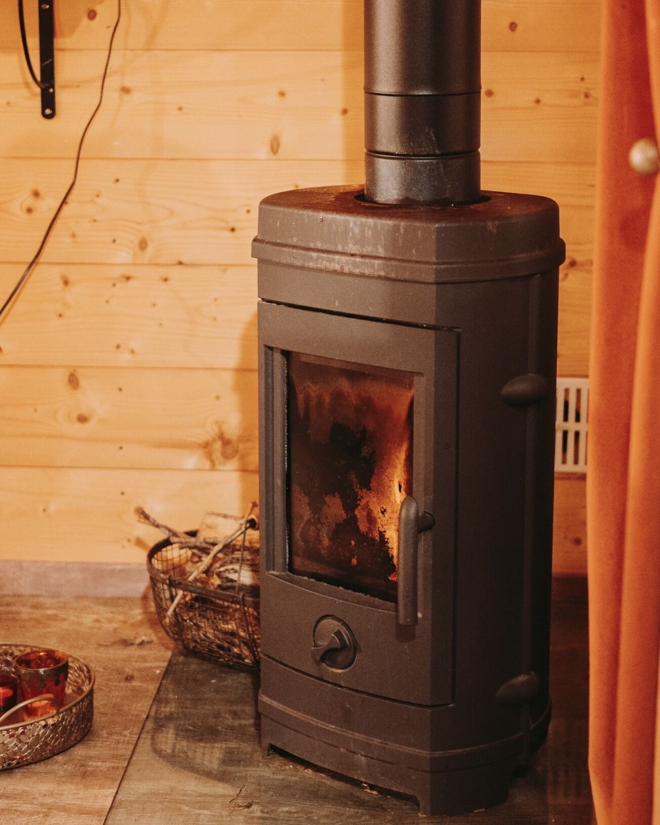 A wood-burning stove with a glass door, a metal handle, and a chimney.