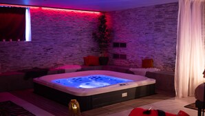 A modern spa room with a hot tub, a potted plant, and a brick wall. - Domaine de la Fauvrière (Sainte-Honorine-de-Ducy)