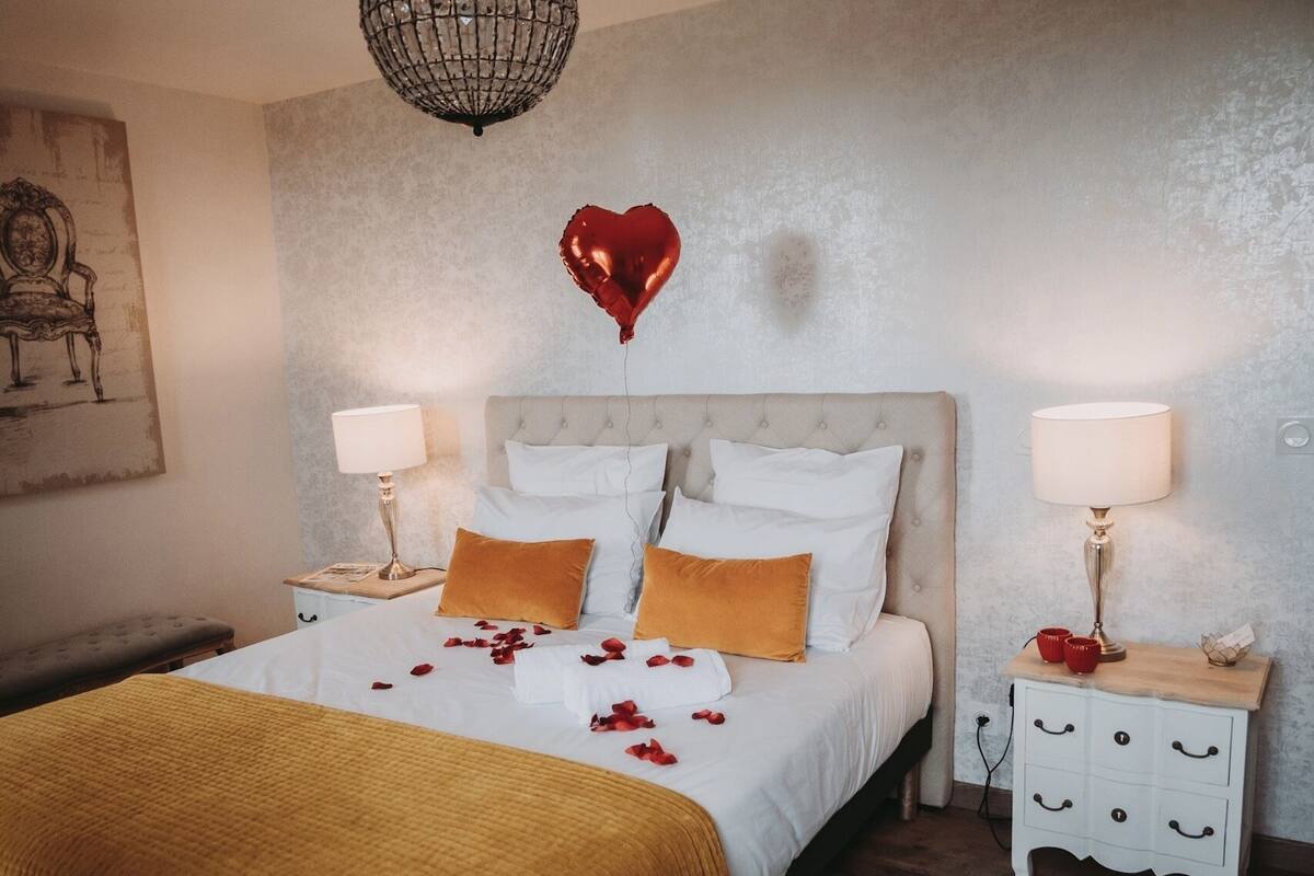 A bedroom with a bed, two bedside tables, a hanging light fixture, and a wall-mounted picture.