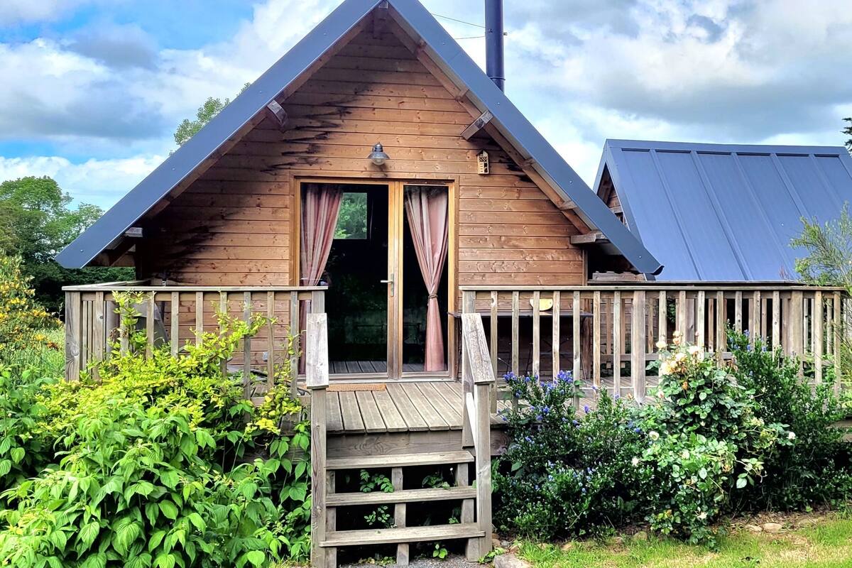 A wooden cabin with a sloped roof, a wooden deck, and a small porch.