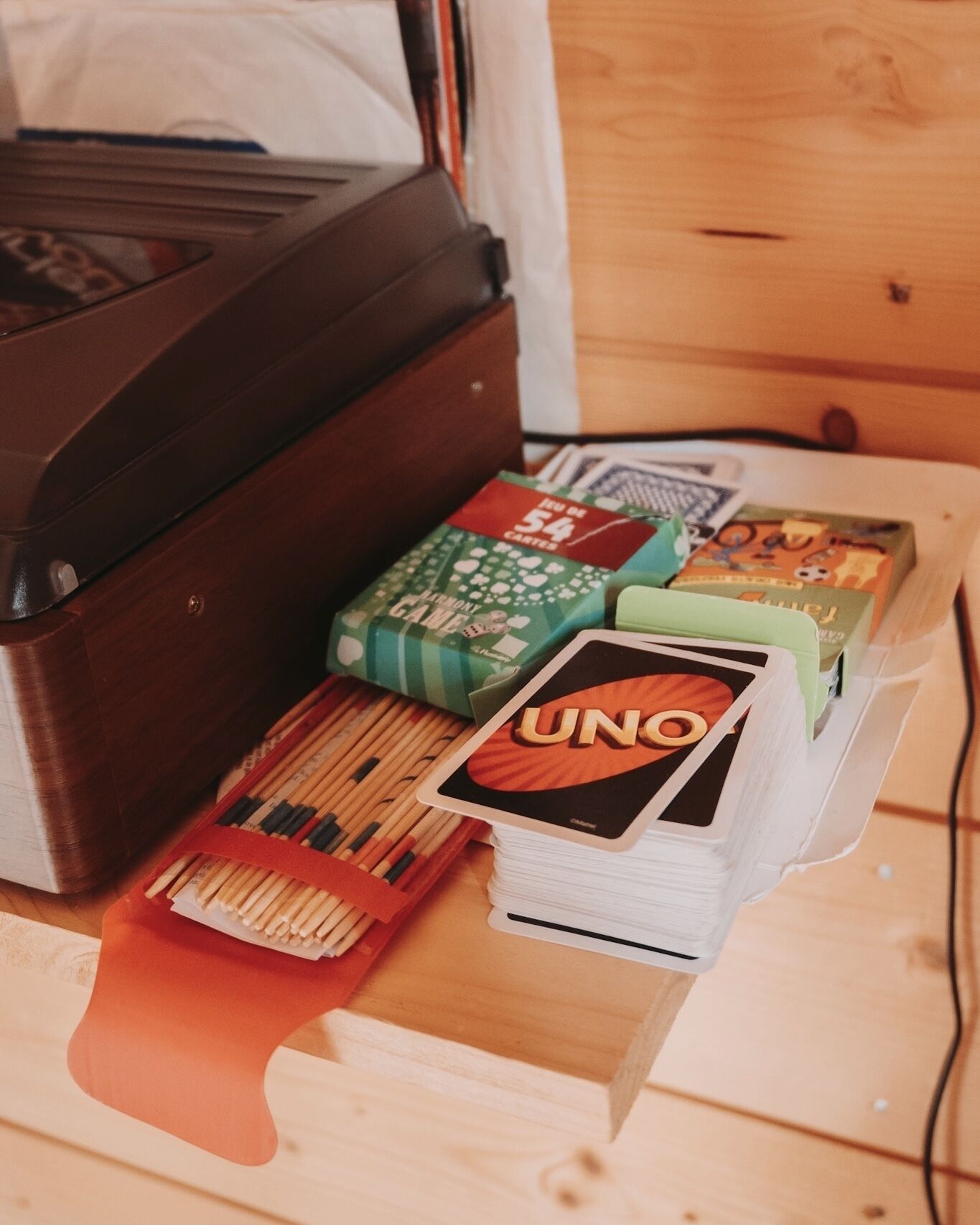 A wooden table with a printer, a deck of UNO cards, and several board games including UNO.