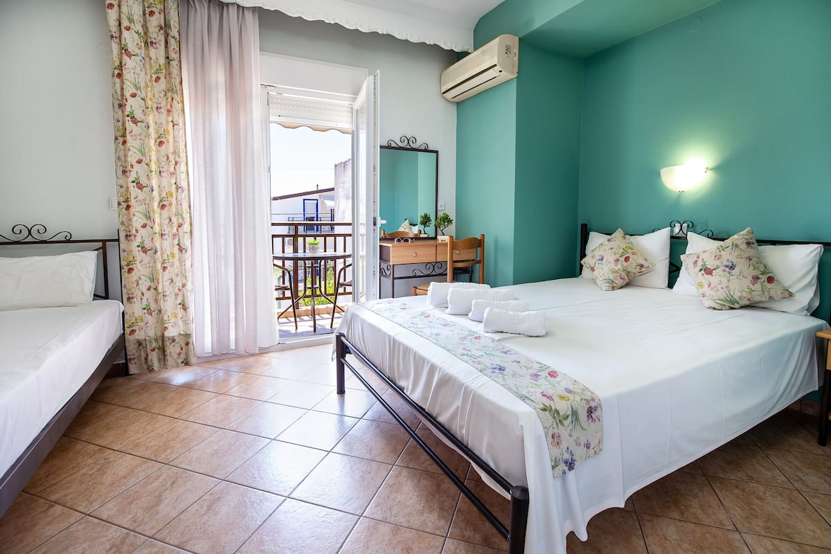 A bedroom with a bed, a dresser, a mirror, and a balcony.