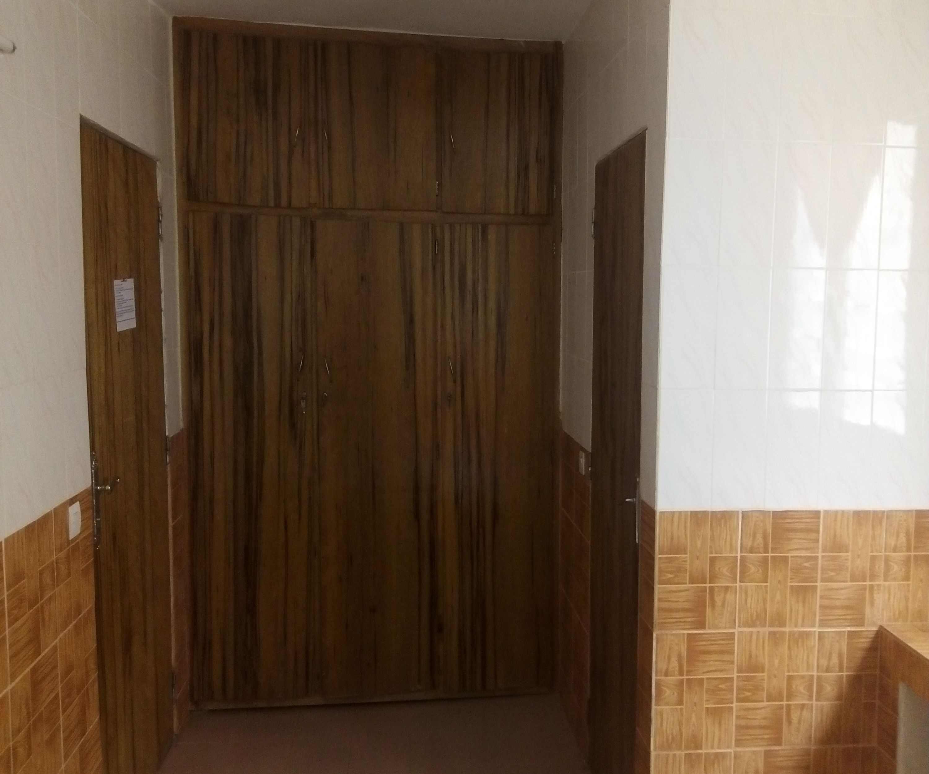 A hallway with a wooden wardrobe and a tiled wall.