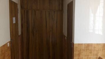 A hallway with a wooden wardrobe and a tiled wall.