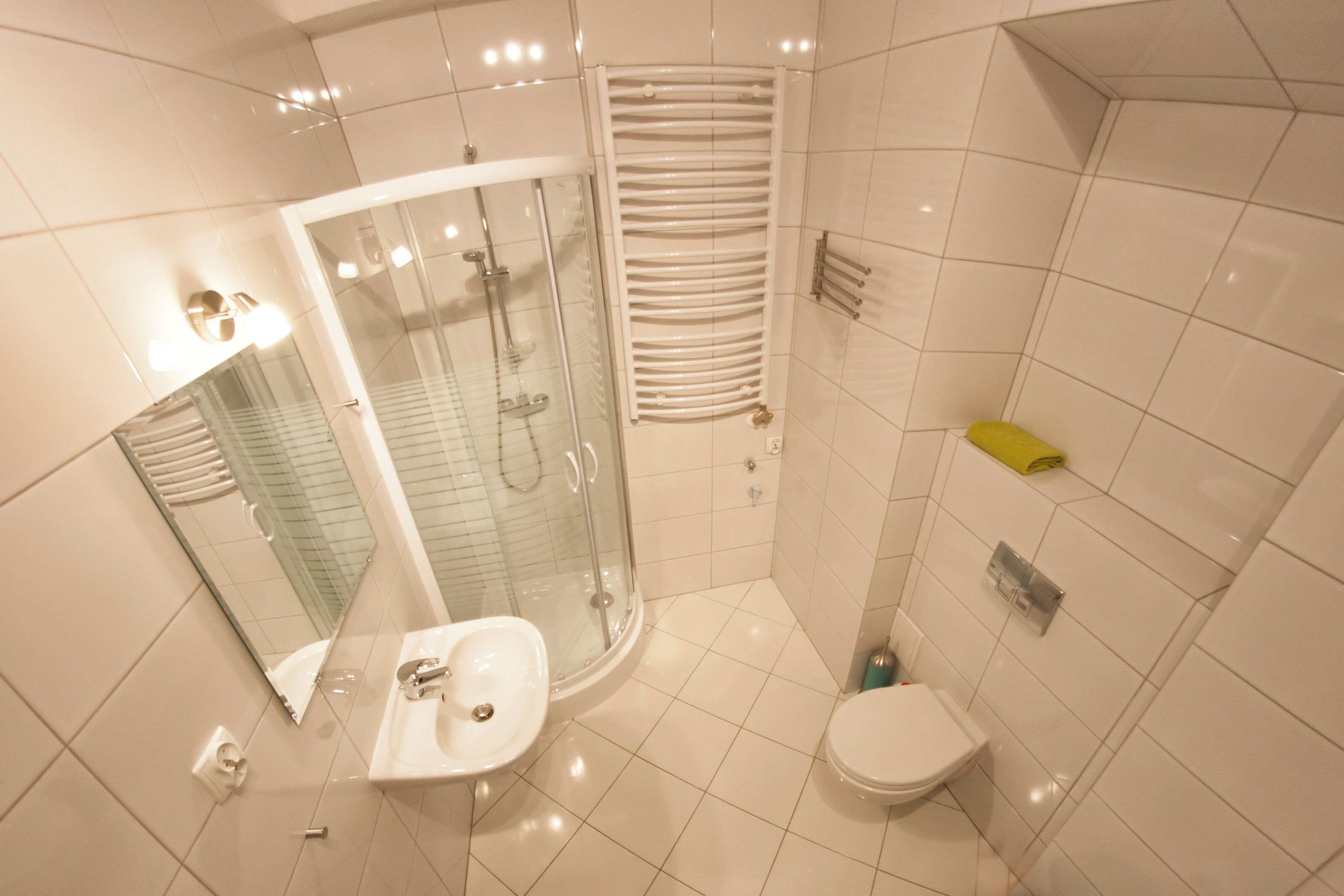 A modern bathroom with a glass-enclosed shower, a sink, a toilet, and a towel rack.