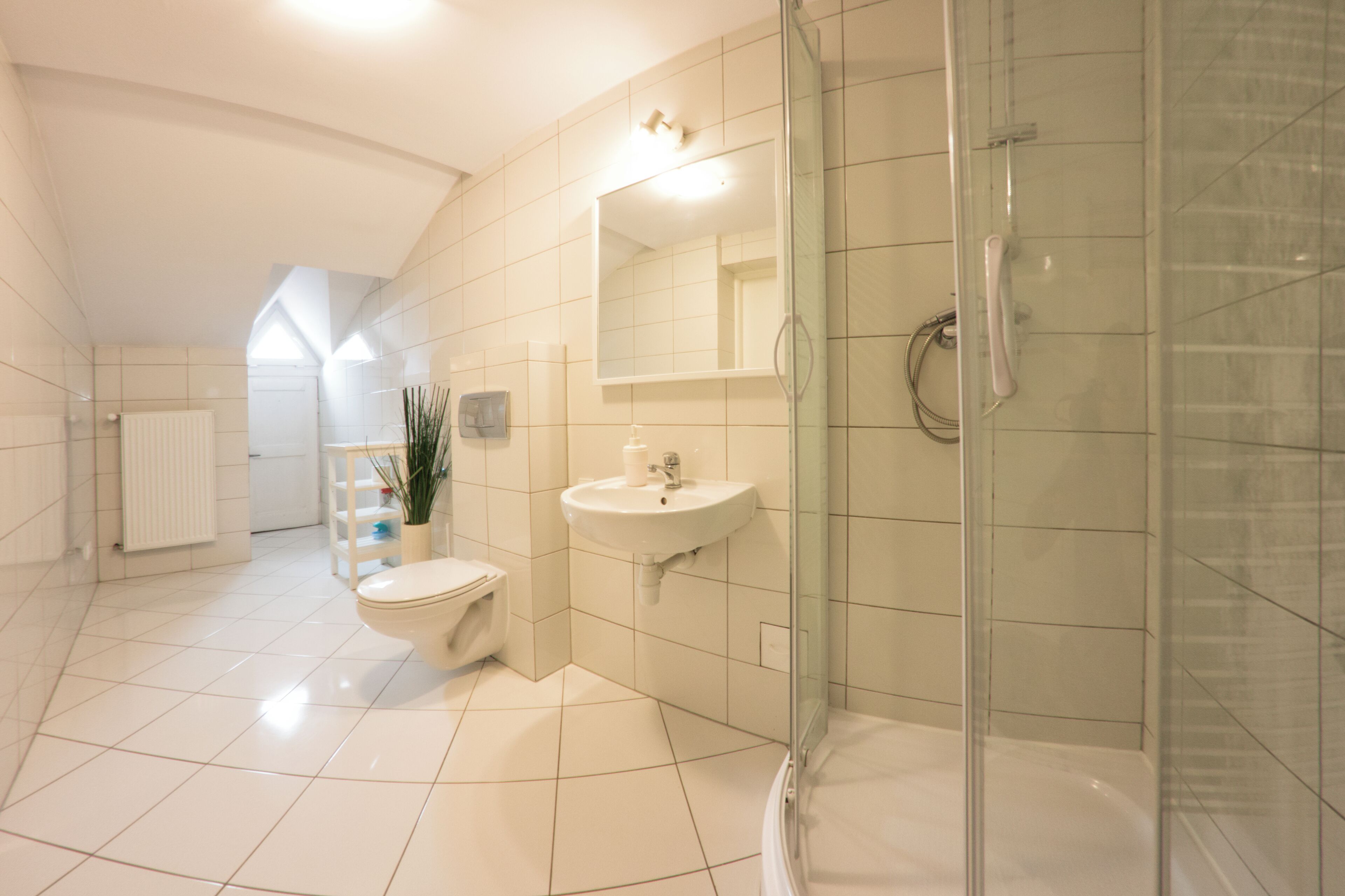 Un baño moderno con ducha de vidrio, lavamanos blanco y retrete.