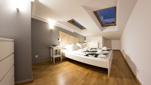 A modern bedroom with a curved bed, skylights, a desk, and a wardrobe. - Fresh Apartments (Kraków)