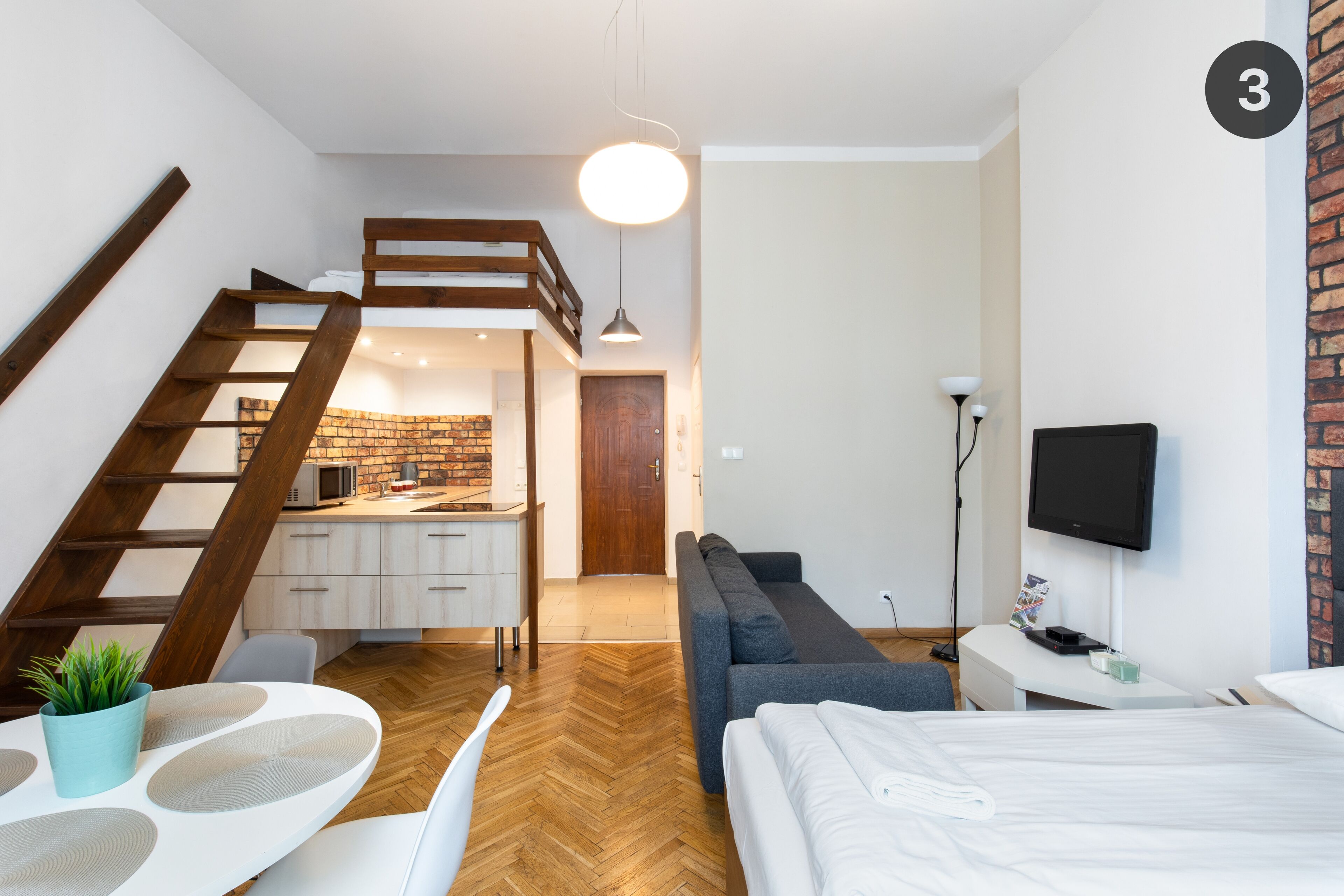 A modern apartment with a loft bedroom, a dining area, and a kitchen.