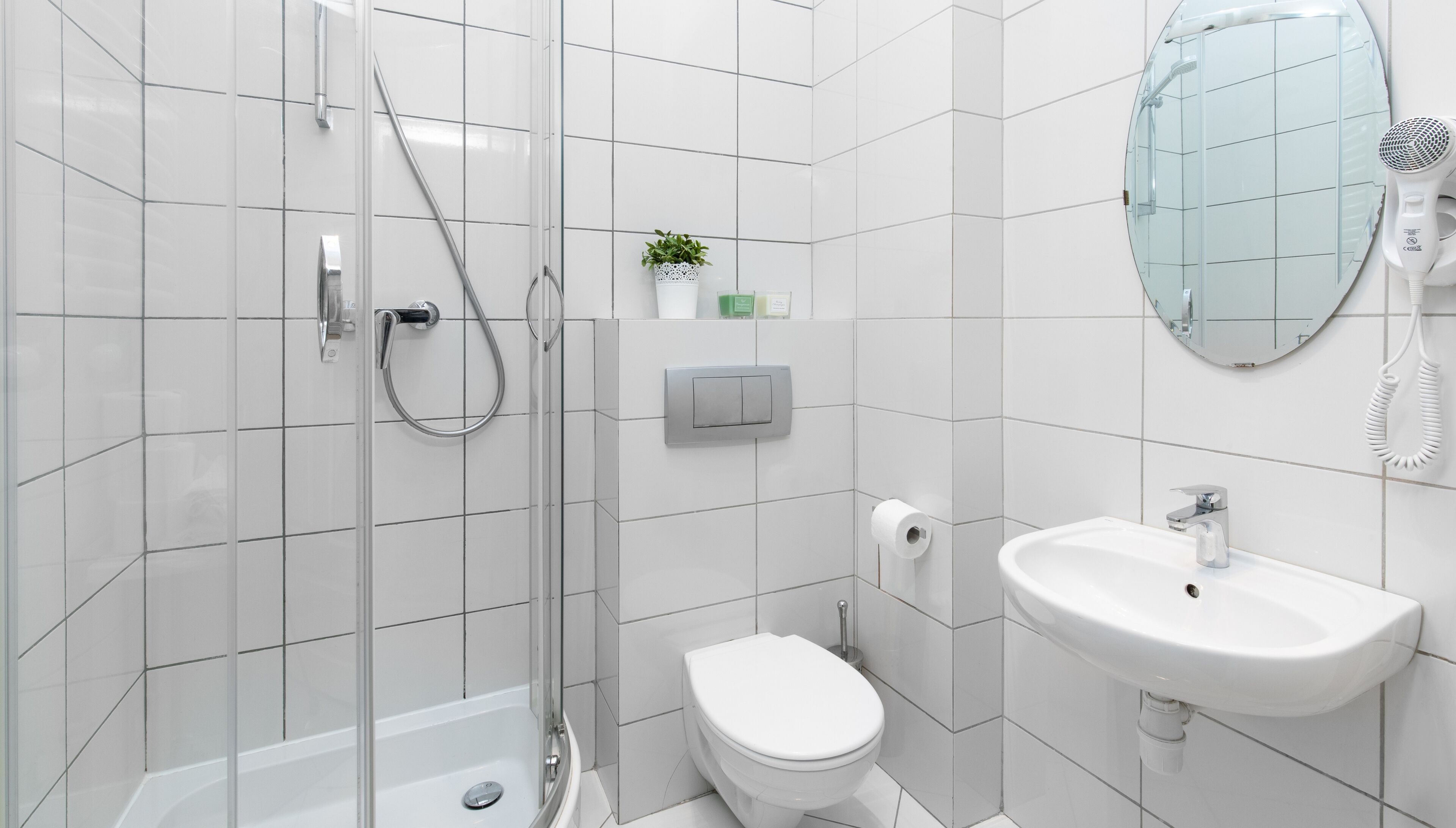 Un baño moderno con cabina de ducha de vidrio, inodoro, lavabo y espejo.