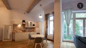 A modern kitchen with white cabinets, a tiled backsplash, and a dining area with a round table and chairs. - Fresh Apartments (Kraków)