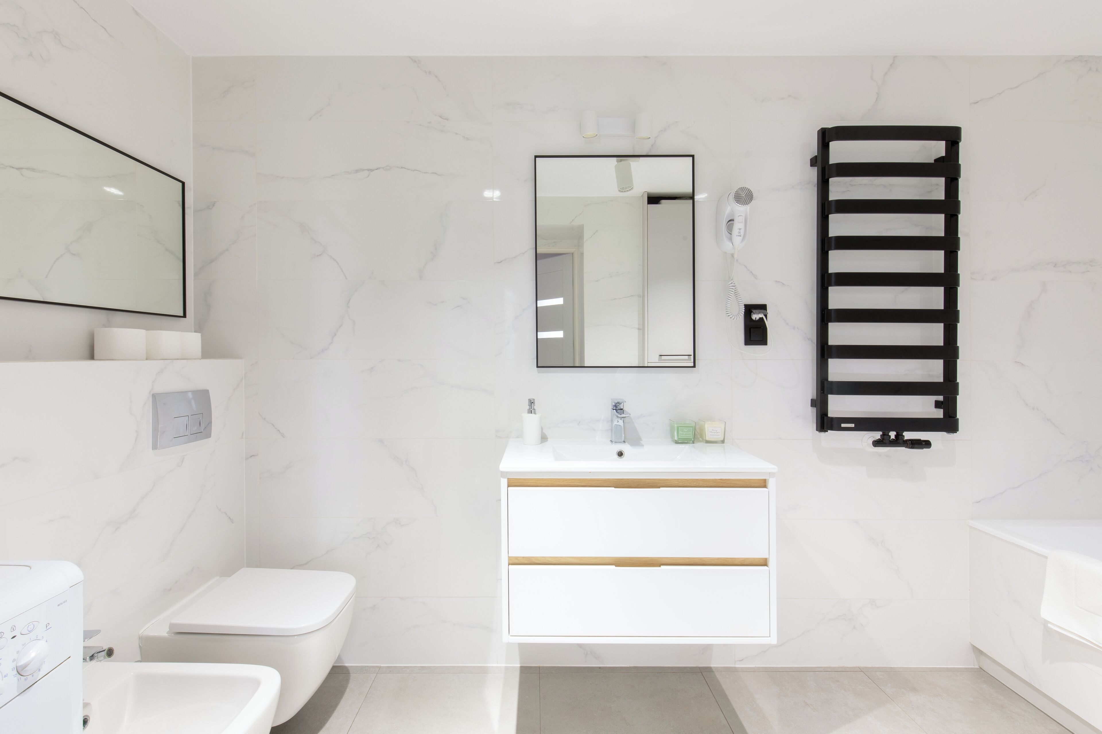 Un baño moderno con tocador blanco, inodoro, bidé y perchero para toallas.