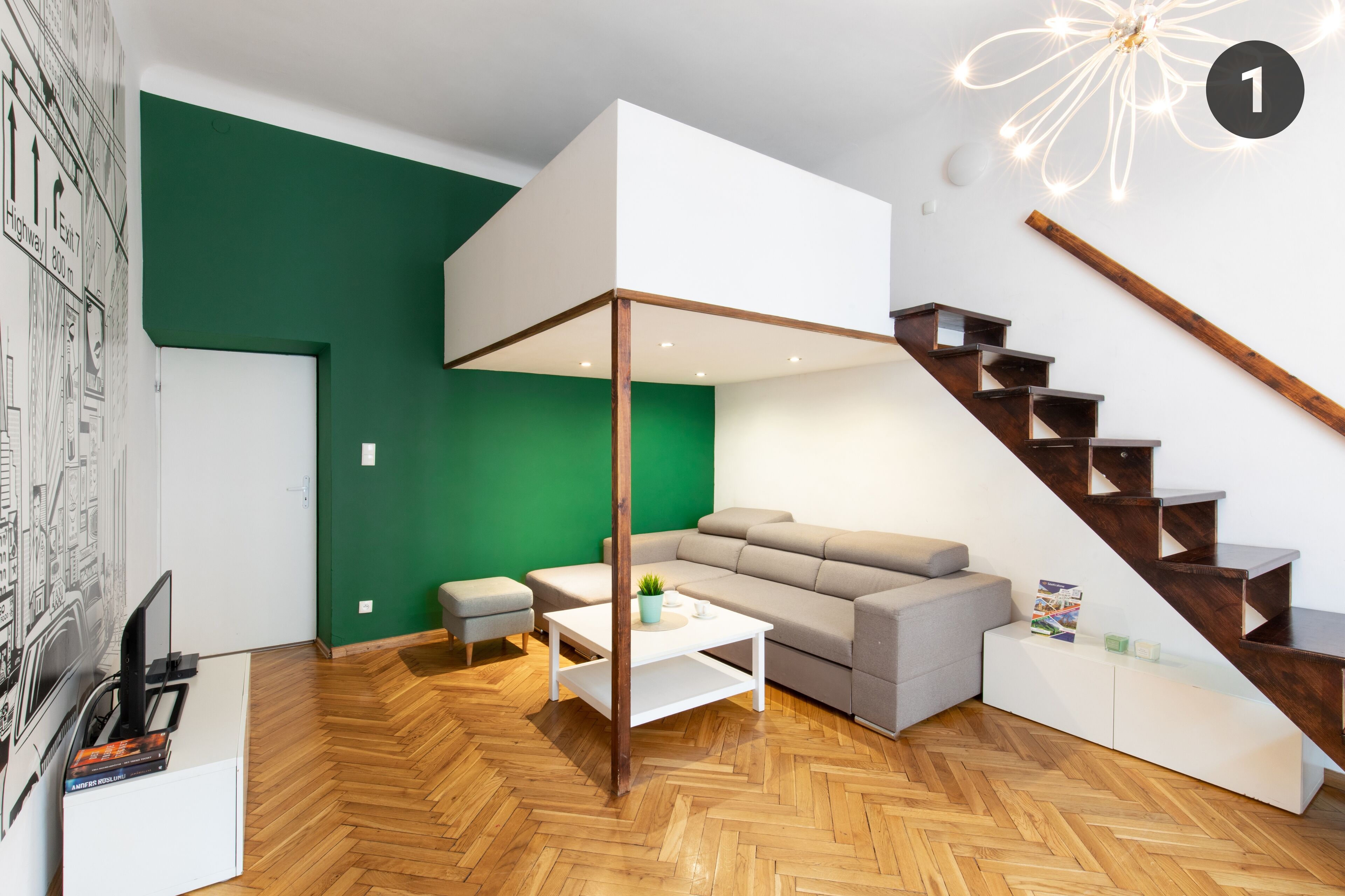 Ein modernes Wohnzimmer mit grüner Akzentwand, einem Ecksofa, einem weißen Couchtisch und einer Holztreppe.