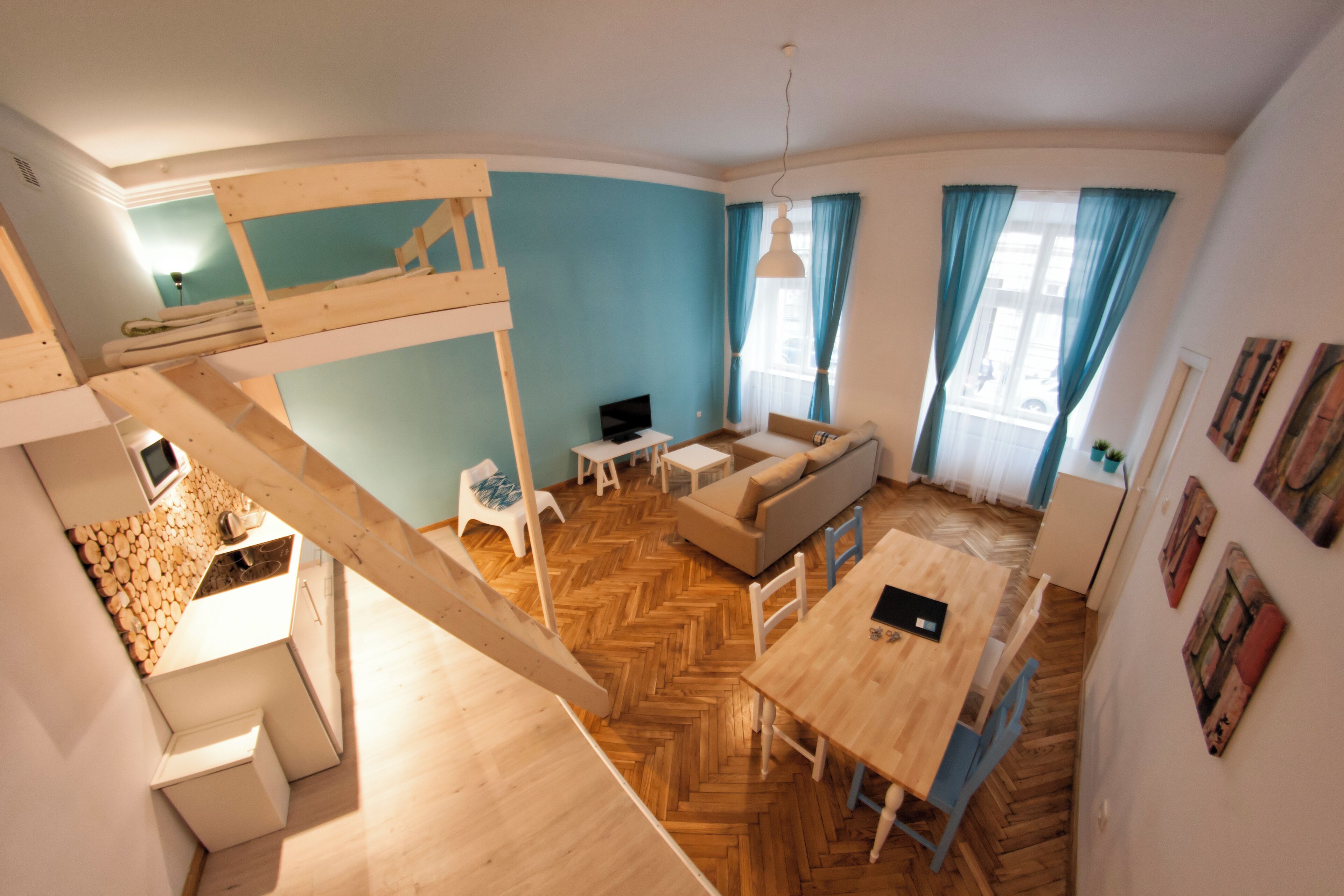 Una habitación compacta y de varios niveles con una cama litera, un sofá, una mesa de comedor y una pequeña cocina.