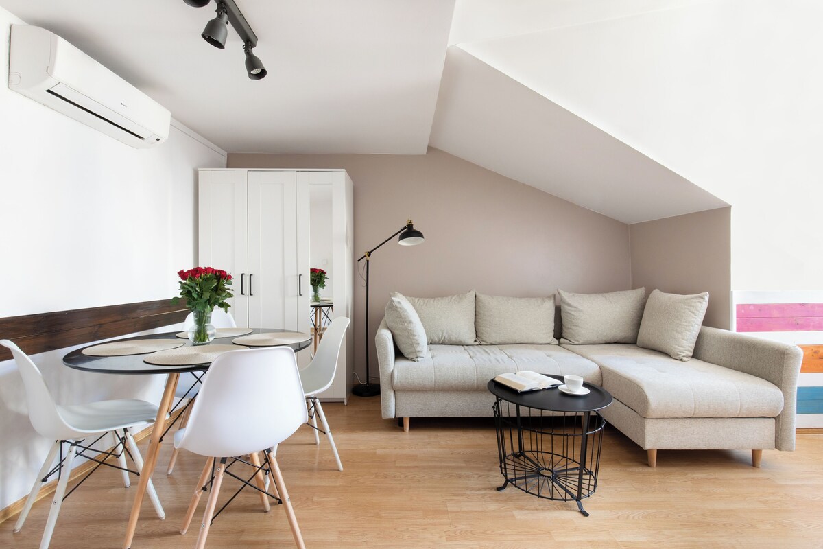 A modern living room with a sofa, dining table, chairs, and a lamp.