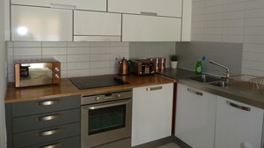 A modern kitchen with white cabinets, stainless steel appliances, and a wooden countertop.