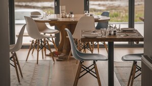 A dining area with a wooden table set for four, surrounded by modern chairs. - Hame Hotel (Dunvegan)