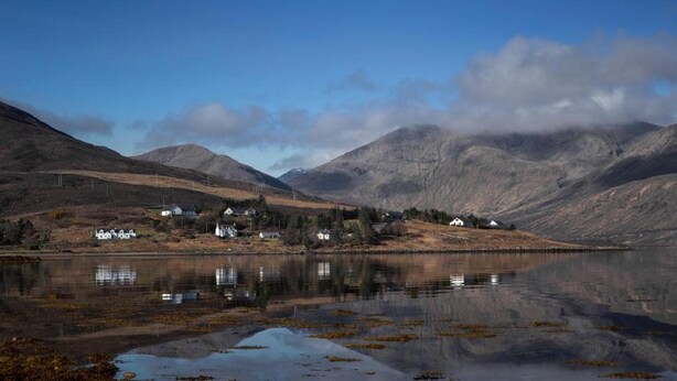 A tranquil lakeside village with houses along the shore, surrounded by mountains. - Hame Hotel (Dunvegan)