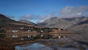 A tranquil lakeside village with houses along the shore, surrounded by mountains. - Hame Hotel (Dunvegan)
