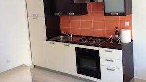A compact kitchen with white and black cabinets, a gas stove, and a built-in oven.