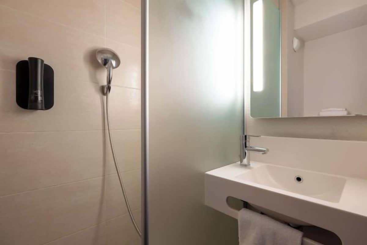 Une salle de bain moderne avec une douche, un lavabo et un miroir.