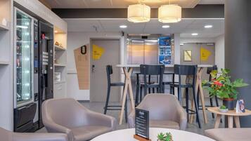 Un hall d’hôtel moderne doté d’un kiosque en libre-service, d’un espace détente et d’un comptoir d’accueil.