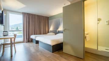 Una camera d'albergo con un letto, una scrivania e una finestra con tende.