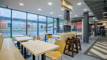 A modern restaurant with large windows, multiple seating areas, and a clean, contemporary design.