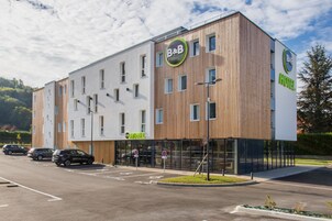 Un hotel tipo B&B moderno con fachada de madera, múltiples ventanas y cielo despejado.