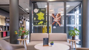 A modern interior with seating areas, a menu board, and informational posters. - B&B HOTEL ANNEMASSE Saint-Cergues (Saint-Cergues)