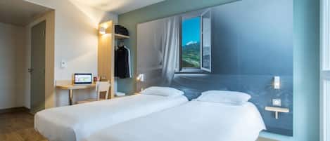 A hotel room with two beds, a desk with a computer, a chair, and a large window with a mountain view.