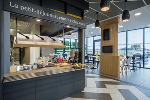 Un café moderno con mostrador de autoservicio, un amplio ventanal con vistas al exterior y un letrero sobre el mostrador que dice 