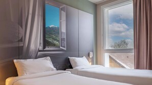 A hotel room with two beds, a large window with a mountain view, and a modern design. - B&B HOTEL ANNEMASSE Saint-Cergues (Saint-Cergues)