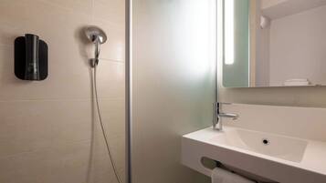 A bathroom with a shower, a sink, and a mirror.