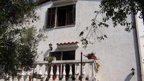 A white building with a balcony, potted plants, and a window with shutters. - Impact villas (Rasa)