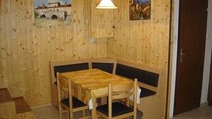 A wooden dining area with a table and chairs, a bench, and two paintings on the wall. - Impact villas (Rasa)