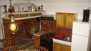 A compact kitchen with wooden cabinets, a stove, a refrigerator, and a dining table with chairs. - Impact villas (Rasa)