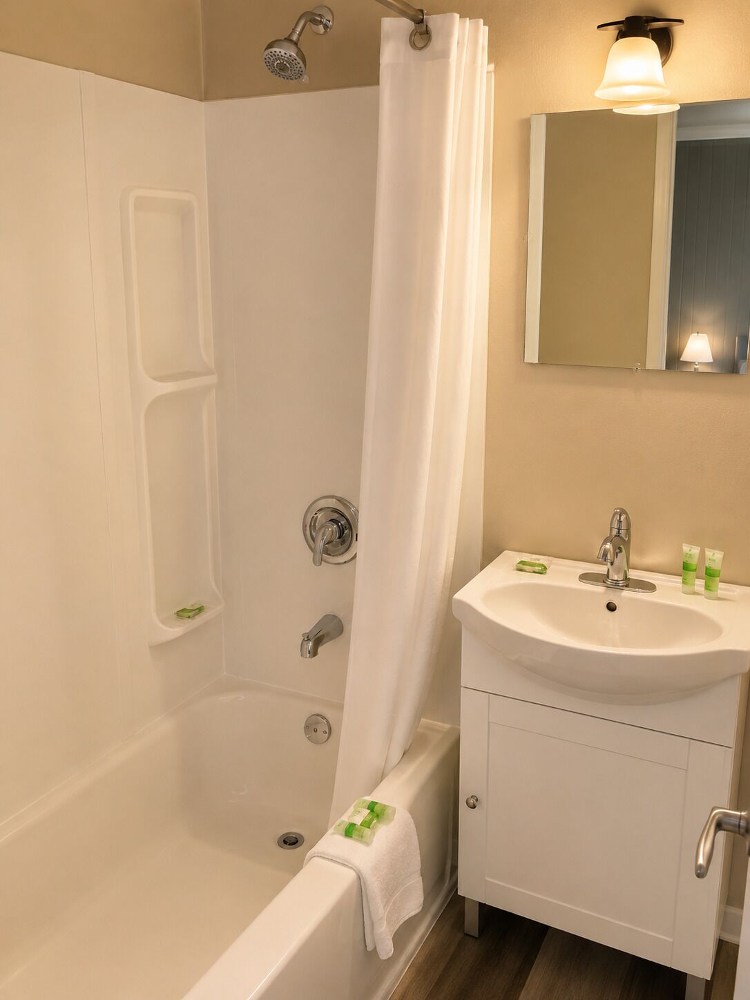 Een badkamer met een bad, douche, wastafel en spiegel.