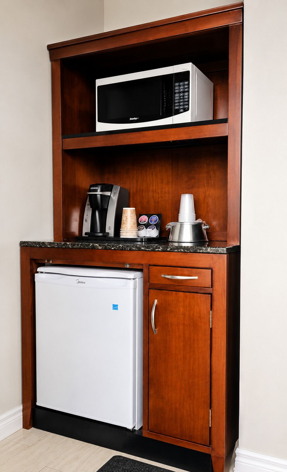 A compact kitchenette with a microwave, coffee maker, and refrigerator.
