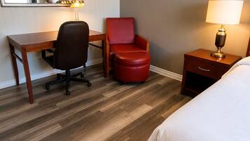 Habitación de hotel con cama, escritorio, silla, mesita de noche, lámpara y un cuadro en la pared de la Torre Eiffel.