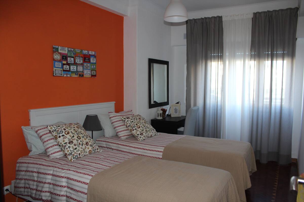 Una habitación de hotel con dos camas, una mesita de noche, un espejo y una pared con diplomas.