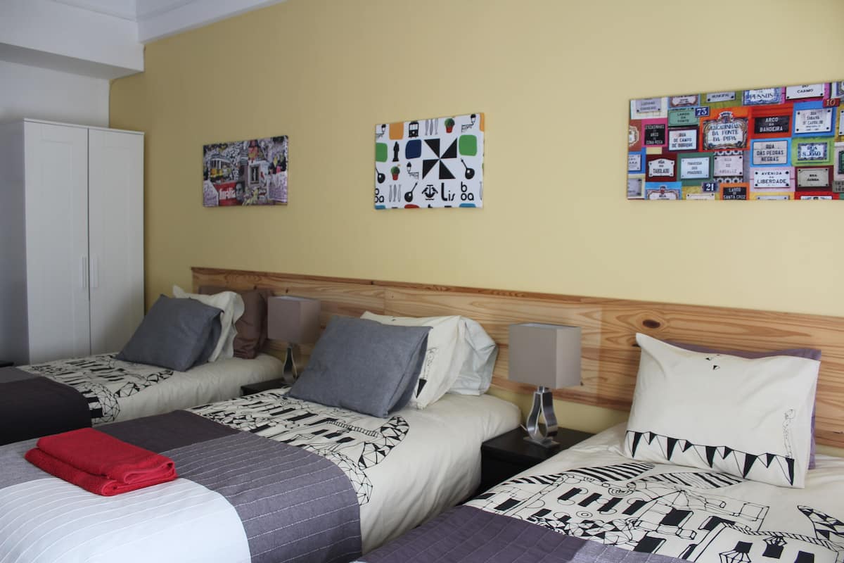 Habitación de hotel con dos camas, cada una con almohada y manta. Se observan adornos en la pared y un armario blanco.