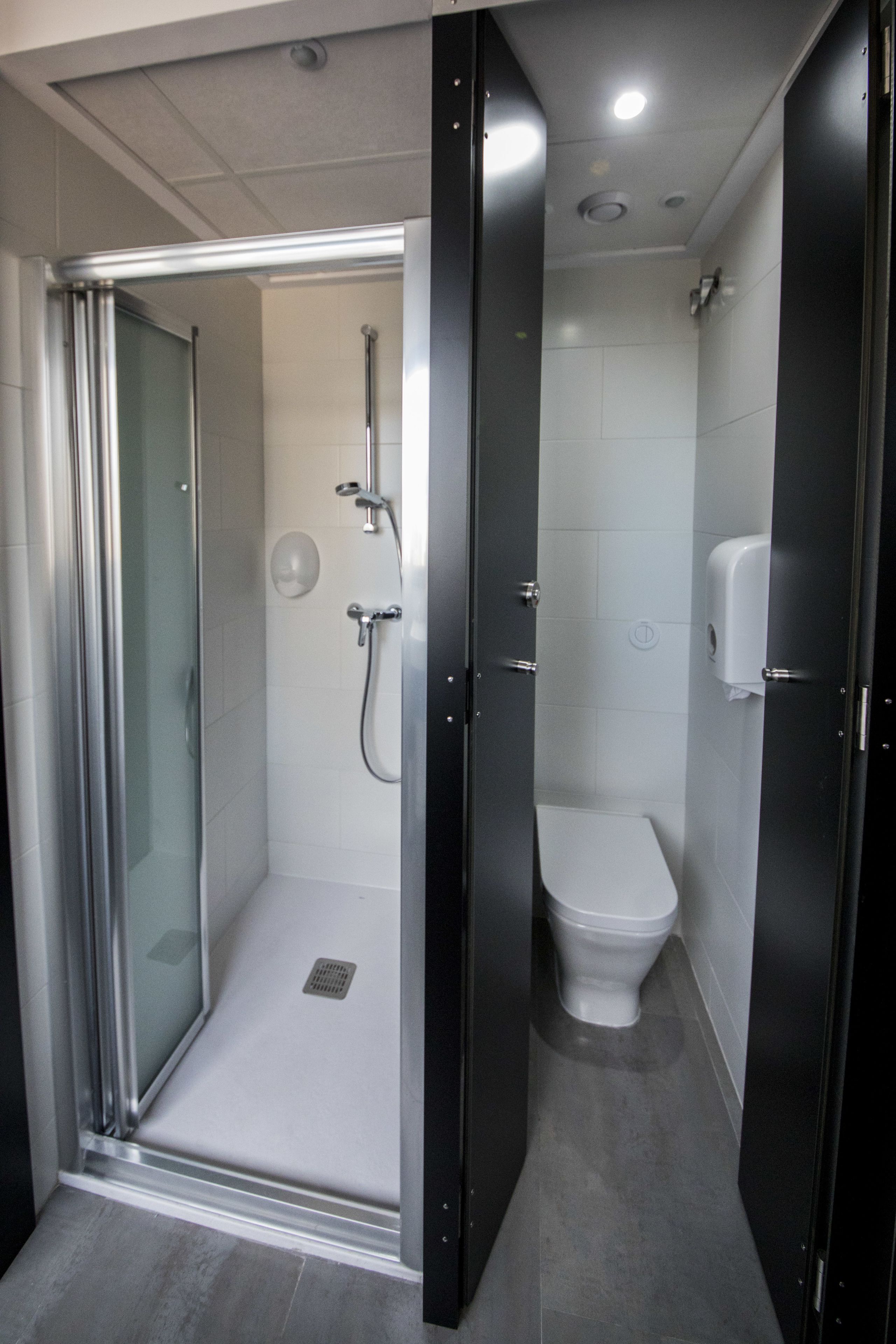 Un baño moderno con ducha de mampara de vidrio, inodoro y secamanos.