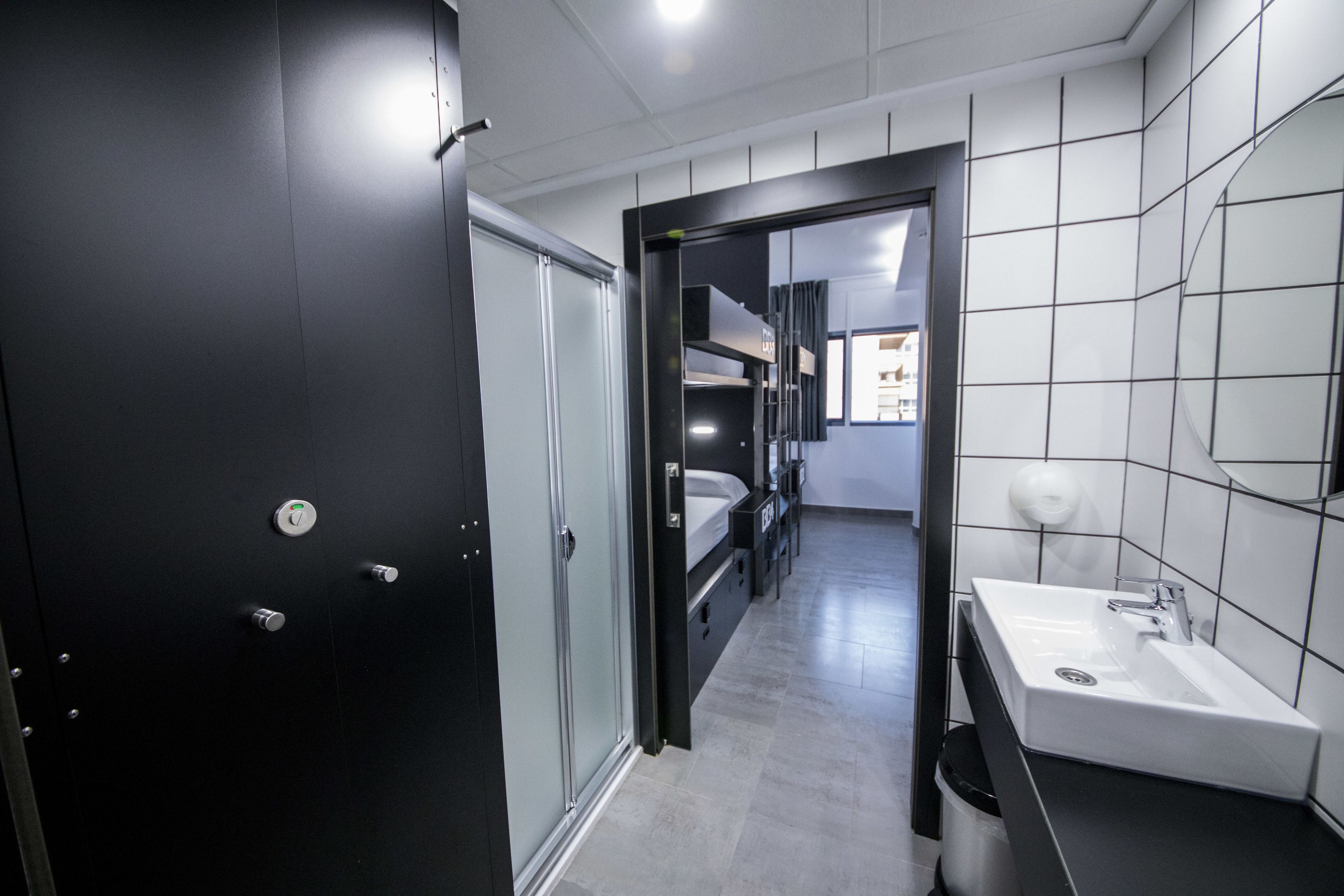 A modern bathroom with a black door, a white sink, and a mirror.