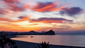 Ein Küsten-Sonnenuntergang mit einer markanten Hügelkette und einer kleinen Insel.
