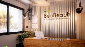 Ein Empfangsbereich bei BeaBeach mit einem Laptop, einer Pflanze und einem Schild, das einen 24-Stunden-Service anzeigt.