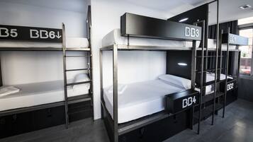 Habitación tipo dormitorio con literas identificadas como BB5, BB6, BB3, BB4 y BB2. Cada litera tiene una escalera y un pequeño cajón para guardar objetos.