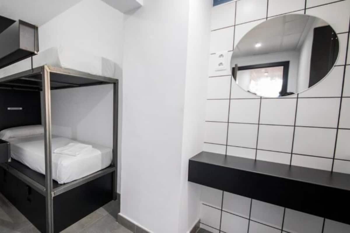 A bunk bed room with a mirror and a tiled wall.