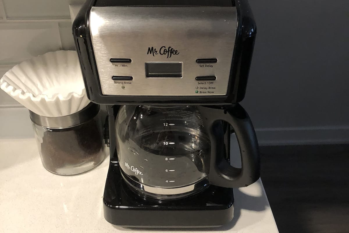 A Mr. Coffee coffee maker on a countertop with a paper filter basket and a glass carafe.